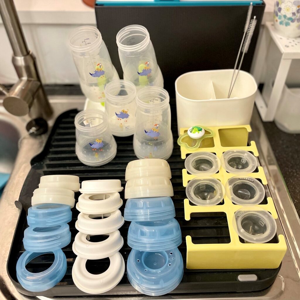 Author's MAM bottles deconstructed on kitchen sink drying rack next to bottle station