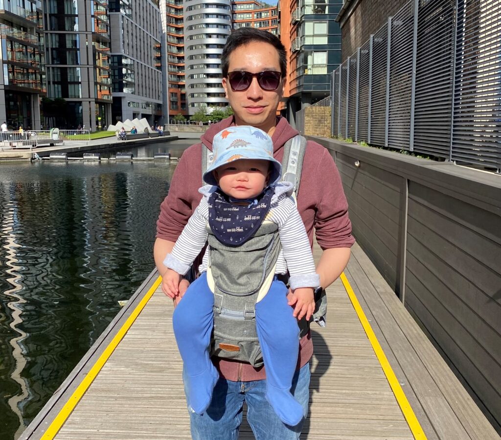 Father carrying 10 month old baby in the Amazon Sunveno hip seat carrier by the canal