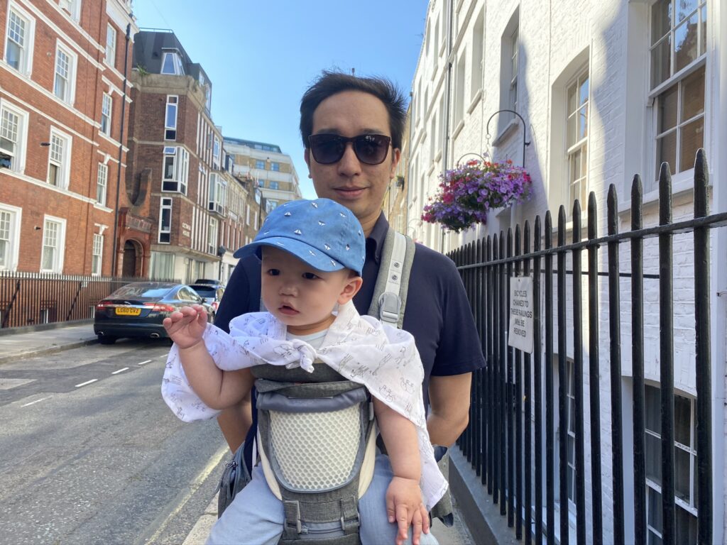 Father carrying 10 month old baby in the Amazon Sunveno hip seat carrier with the front panel unzipped