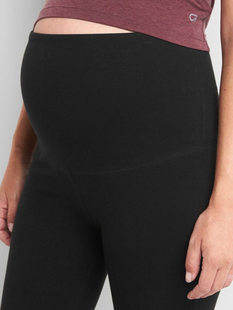 Close up of model wearing Gap maternity full panel capris leggings in true black - showing the full panel over bump