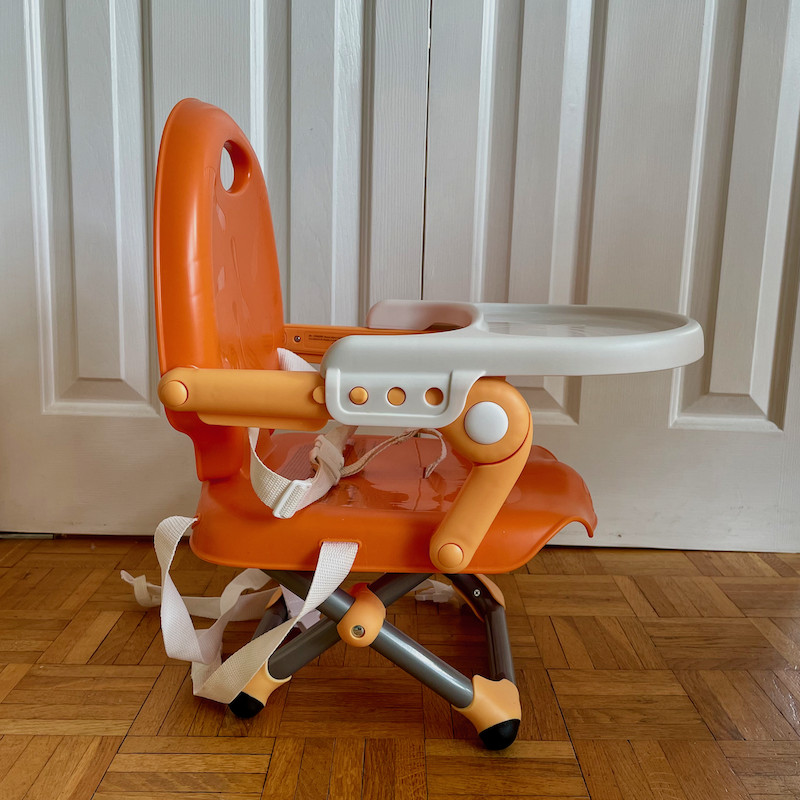 Author's Chicco Pocket Snack Booster Seat in orange with tray and legs folded out side view