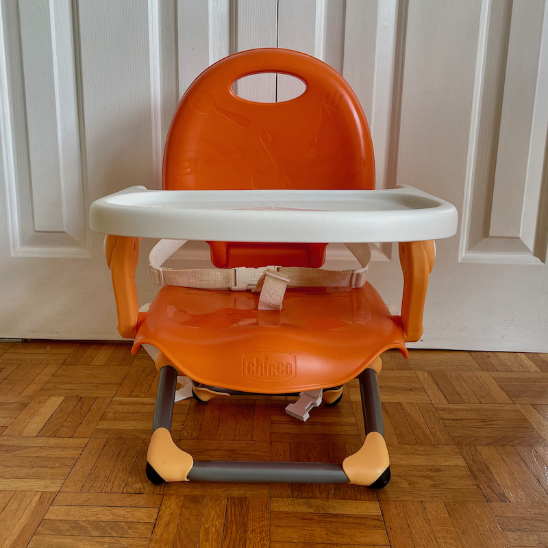 Author's Chicco Pocket Snack Booster Seat in orange with tray and legs folded out front view