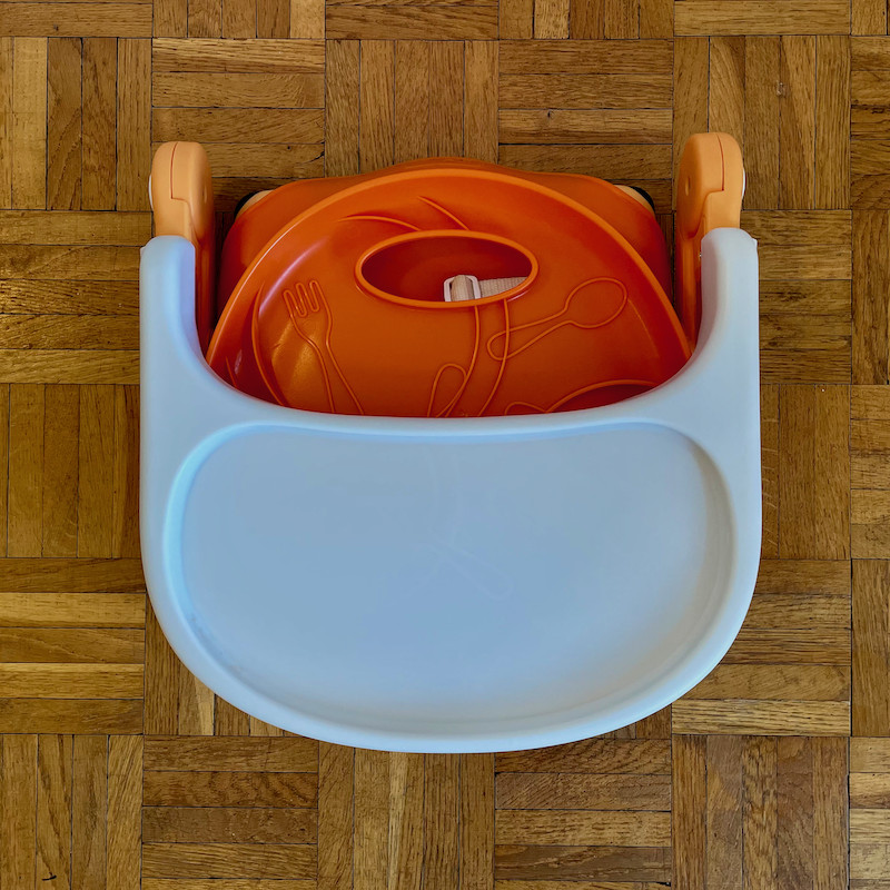 Author's Chicco Pocket Snack Booster Seat in orange folded flat view from above