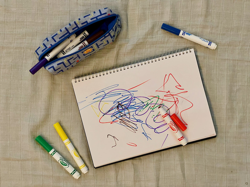 Crayola Pens scattered next to sketchbook